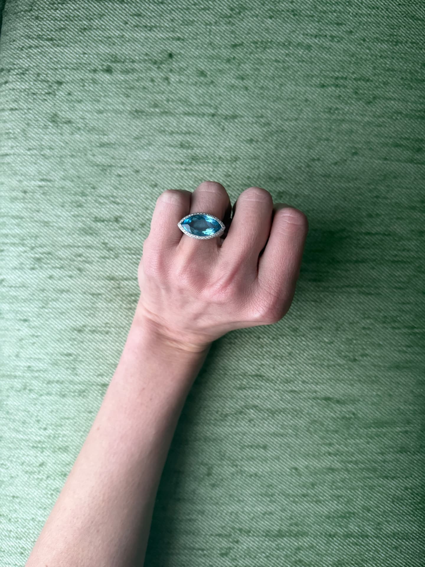 Marquise-cut blue topaz and diamond halo ring worn on a hand