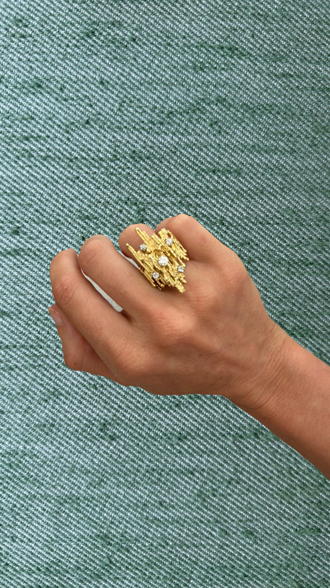 Textured gold modernist ring set with diamonds worn on a hand