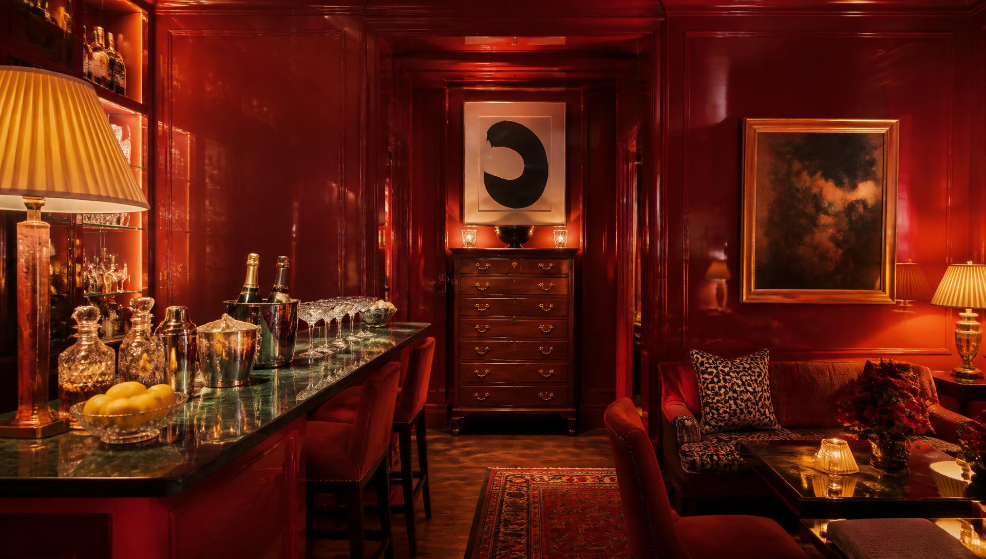 Glossy lacquered red drawing room at night with lamplight, a granite bar and an antique tall boy